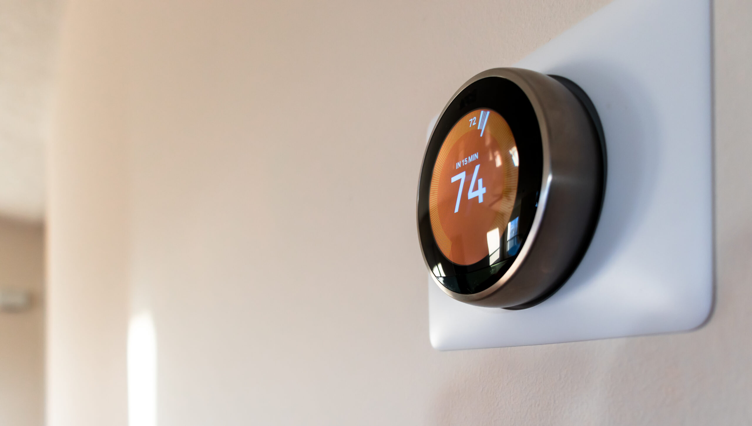 A digital smart thermostat on a wall.